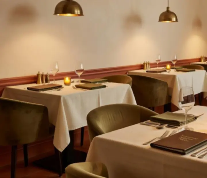An inviting restaurant interior with candlelight, terracotta accents and guests settling in for supper.